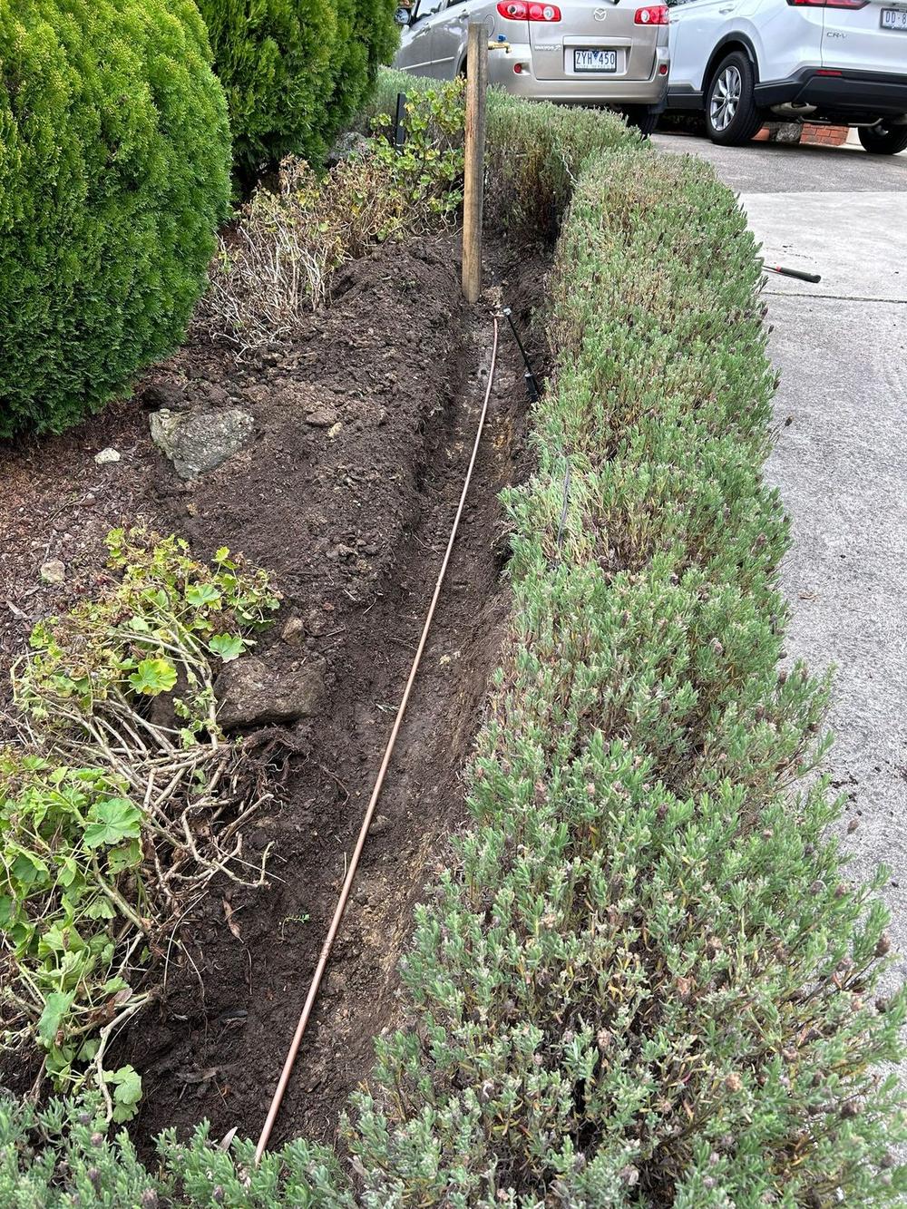 New copper water supply pipe in excavated trench garden bed Altona